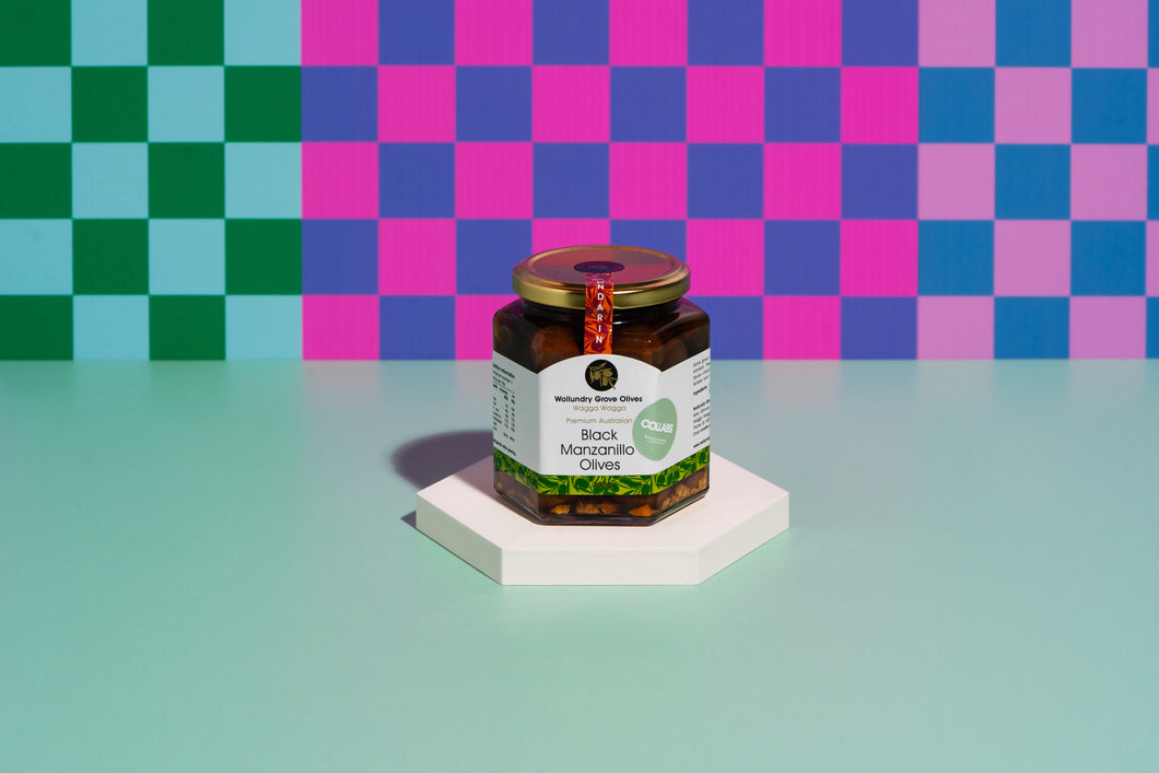 A jar of mandarin infused olives sitting on a white disc with a checkerboard coloured background. 